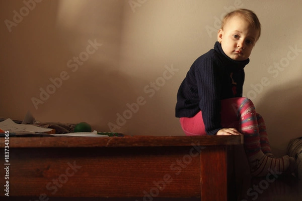 Fototapeta A quiet emotional moment in warm afternoon light. A child pausing in silence, lost in her own thoughts. Copy space for text or design.