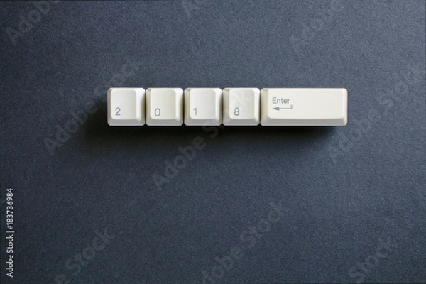 Fototapeta Computer keyboard keys with 2018 enter written using the white buttons on a dark background. Holiday technology concept. New year 2018 card.
