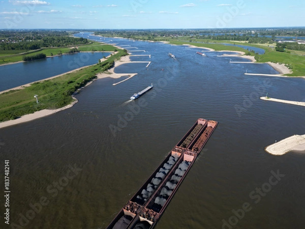 Fototapeta Aerial view of a pusher tug transporting coal on the Waal river to Germany, Rossum, The Netherlands