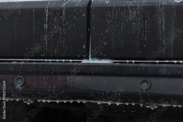 Fototapeta Flowing water reveals bumper textures, Stream of water uncovers seam and runoff details, Flowing streams illustrate bumper seam features and runoff markings in detailed water movement