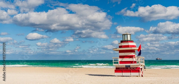 Obraz Lifeguard tower on the sandy Miami Beach shore. Iconic Art Deco lifeguard station under summer sky. Scenic view of South Beach coastline in Florida. Colorful lifeguard tower, symbol of Miami tourism.