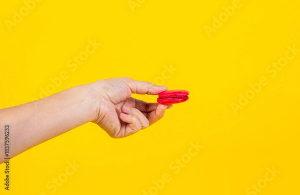 Fototapeta Red macarons in hand on yellow background