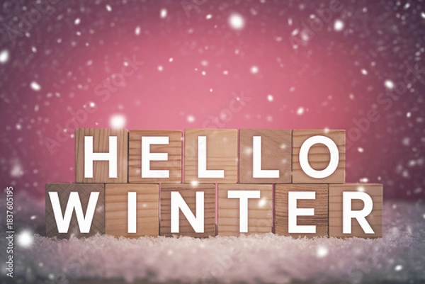 Obraz Wooden blocks spelling hello winter with falling snow against a pink background creating a festive seasonal atmosphere.