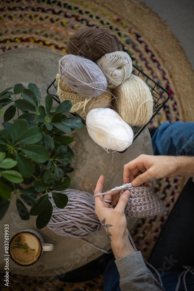 Obraz Male hands crochet handmade artwork use wool yarn and hook over table with coffee top view