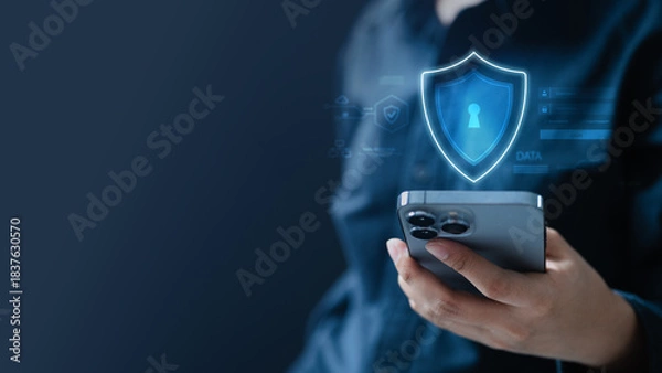 Fototapeta A digital privacy and security concept showing a glowing shield hologram above a smartphone, representing data protection, encryption, secure communication.