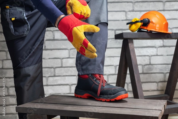 Obraz Construction worker putting on the gloves and hard hat preparing for work.