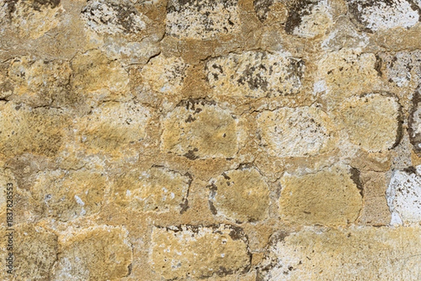 Obraz The wall is constructed of light brown round and oval stones bonded with cement and lime mortar. Traces of lichen are visible.