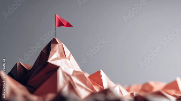 Fototapeta A red flag on the mountain peak. The flag is on top of a mountain made of folded paper and indicates reaching goal