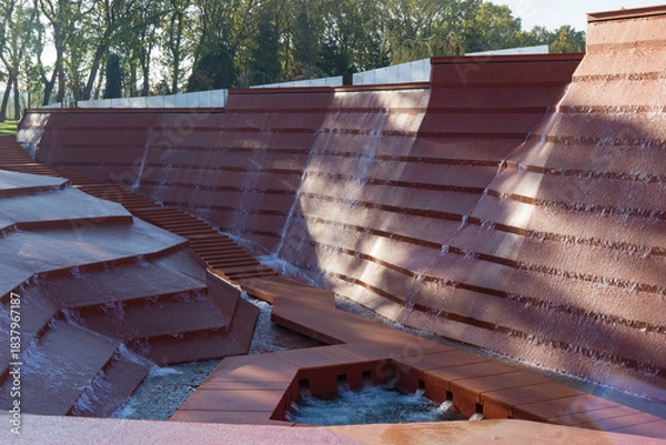 Obraz Large-scale fountain with cascading water flowing down stepped tiers into geometric pool, set against backdrop of trees. Amphitheater of water or Canyon in Public city park Krasnodar or Galitsky Park