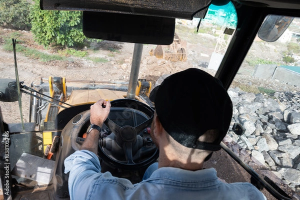 Obraz Young man driving a backhoe loader in the countryside