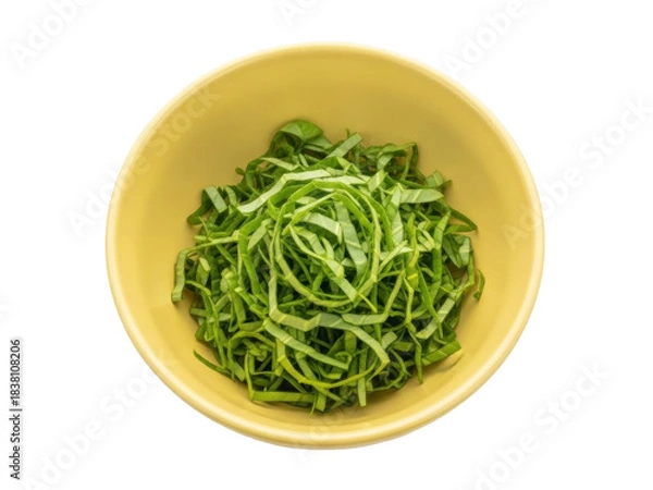 Fototapeta Isolated image of freshly chopped green cabbage leaves in a yellow bowl, ready for cooking