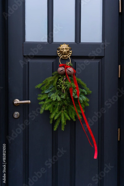 Obraz Close-up of a beautiful Christmas wreath with red ribbon and bells on a black door

