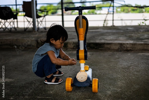 Obraz Focused Toddler Fixing Scooter