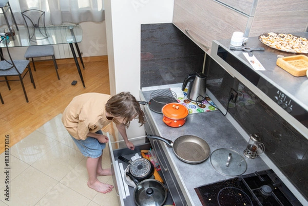 Obraz Person searching in a messy kitchen drawer for a pot. High angle view of domestic life