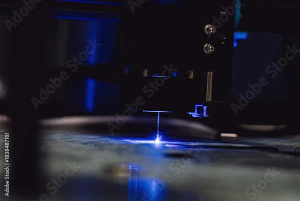 Obraz Close up of laser cutting paronite. Powerful blue laser burning complex gasket shape out of asbestos material. Smoke and sparks visible during precise manufacturing of industrial seals.