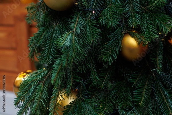 Fototapeta Golden Christmas bauble on fir tree with festive lights and soft bokeh