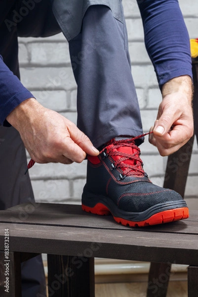 Obraz Worker putting on shoes for work. Safety work concept.