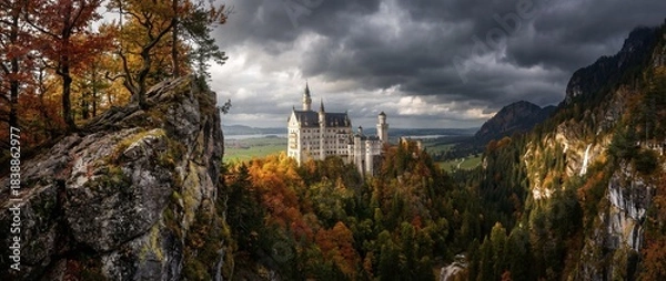 Obraz Castle sits on a hill surrounded by trees and mountains during autumn