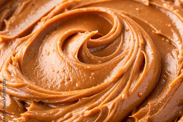 Fototapeta Texture of caramel sauce or peanut butter. Swirl of sweet brown cream closeup. Toffee or dulche de leche background. Melted chocolate or nut paste pattern.