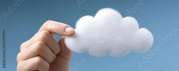 Fototapeta Hand holding white cloud cotton blue sky minimal soft fluffy concept imagination dream creative feeling. Hand holds soft cotton cloud against blue sky, playful minimal concept with airy mood