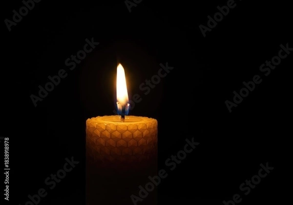 Fototapeta Glowing golden flame on a natural beeswax pillar candle, illuminating a warm, cozy dark setting, perfect for relaxation ,relaxation ,honey scent ,lighting