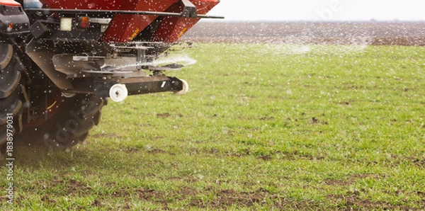 Obraz Tractor spreading artificial fertilizers in field