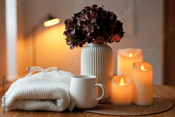 Obraz Cozy winter home interior with warm candlelight, wool sweater, hot tea and LED decor creating a calm hygge atmosphere