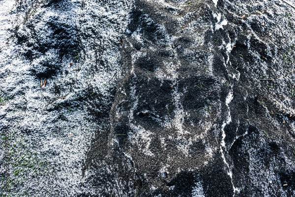 Obraz black rubber granulate mound lightly dusted with winter snow.