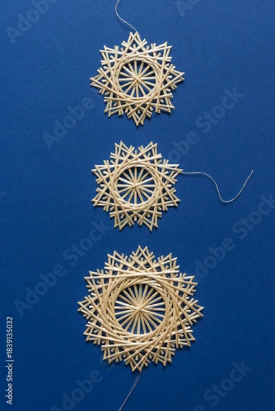 Obraz Snowflakes are made of straw on a blue background. Christmas decor. Top view. Straw weaving. Lutsk, Ukraine