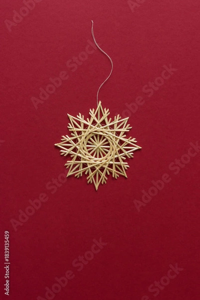 Obraz Straw snowflake. Snowflake are made of straw on a red background. Christmas decor. Top view. Straw weaving. Lutsk, Ukraine
