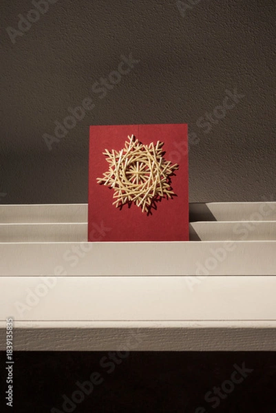 Obraz The straw star is illuminated by the sun. Snowflakes are made of straw on a red background. Straw snowflakes. Straw weaving. Lutsk, Ukraine