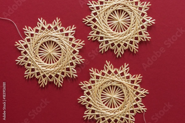 Obraz Straw snowflakes. Snowflakes are made of straw on a red background. Christmas decor. Top view. Straw weaving. Lutsk, Ukraine