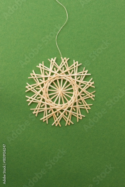 Obraz Snowflakes are made of straw on a green background. Straw snowflakes. Christmas decor. Straw star. Top view. Straw weaving. Lutsk, Ukraine