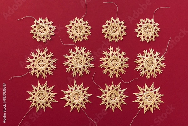Obraz Straw snowflakes. Snowflakes are made of straw on a red background. Christmas decor. Top view. Straw weaving. Lutsk, Ukraine