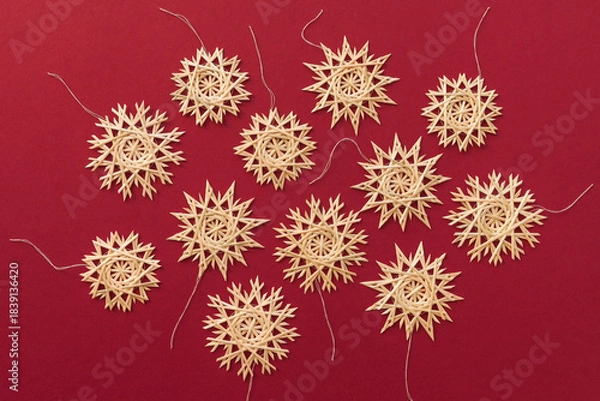 Obraz Straw snowflakes. Snowflakes are made of straw on a red background. Christmas decor. Top view. Straw weaving. Lutsk, Ukraine