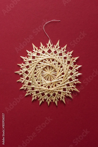 Obraz Straw snowflake. Snowflake are made of straw on a red background. Christmas decor. Top view. Straw weaving. Lutsk, Ukraine