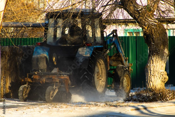 Fototapeta View of a Heavy Blue Utility Tractor Equipped with a Front Loader, Actively Pushing Snow by the Roadside