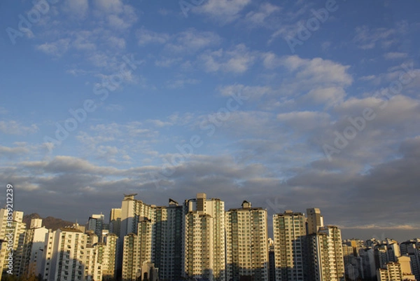 Obraz Landscape with a sky with fluffy clouds and an apartment building