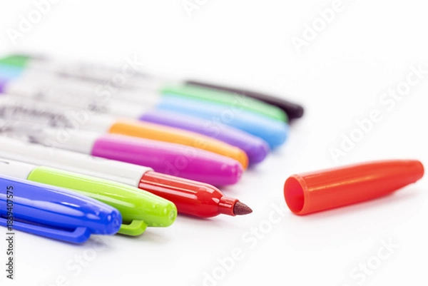 Obraz Close-up of colorful markers lined up on a white background with an uncapped red marker and its red cap beside it
