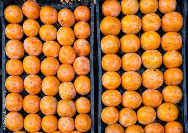 Fototapeta Fresh ripe persimmons displayed in crate.