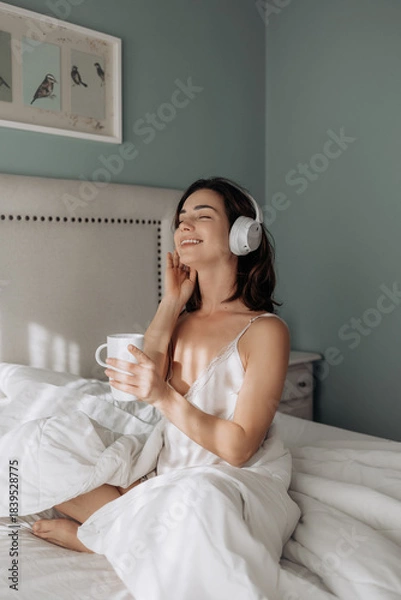 Obraz Woman, headphones and happy on bed, relax and eyes closed with streaming subscription in home. Girl, person and smile with audio tech, sound and listening to music