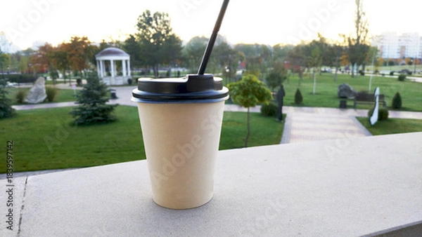 Obraz disposable cup with a hot drink in hand, in a city park. hot warming drink during autumn blues. warms, gives warmth and lifts the mood. tea, coffee, cappuccino or hot chocolate