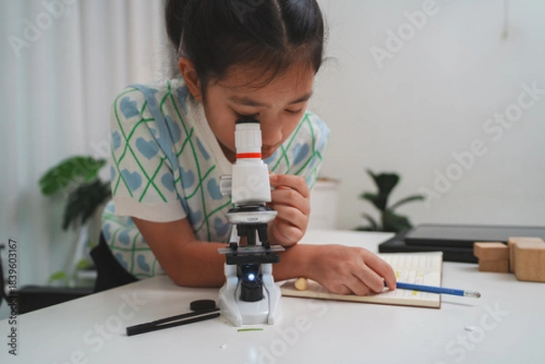 Obraz Elementary student practicing science skills using microscope during hands on learning activity