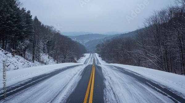 Obraz Winter road through snowy mountains in a remote area during a cloudy day