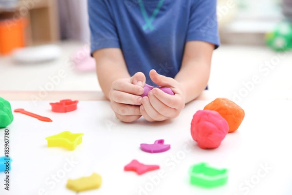 Fototapeta Little boy engaged in playdough modeling at daycare