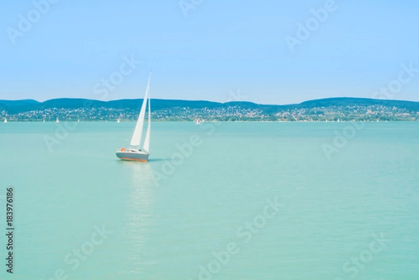 Fototapeta A view from a ship to bright Balaton lake water and a white yacht on sunny summer day, Hungary.