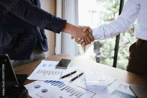 Fototapeta Business team analyzing financial charts and using a calculator during a meeting.
