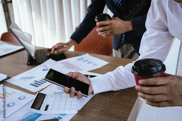 Fototapeta Business team analyzing financial charts and using a calculator during a meeting.