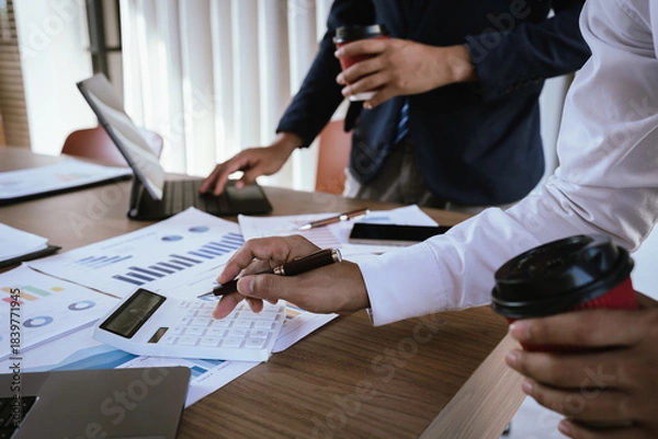 Fototapeta Business team analyzing financial charts and using a calculator during a meeting.
