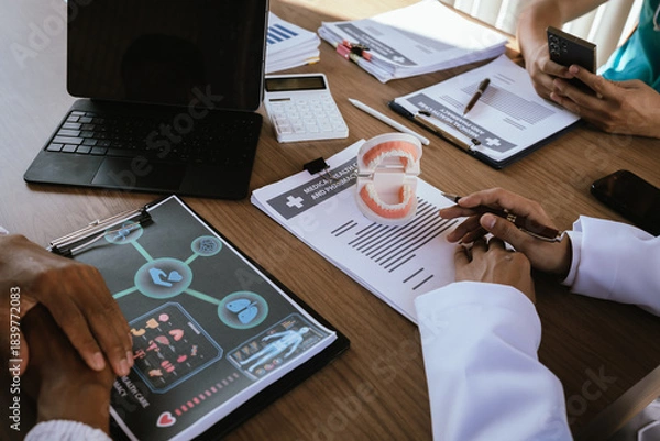 Fototapeta Dental professionals discussing treatment plans with a tooth model and medical documents during a meeting.